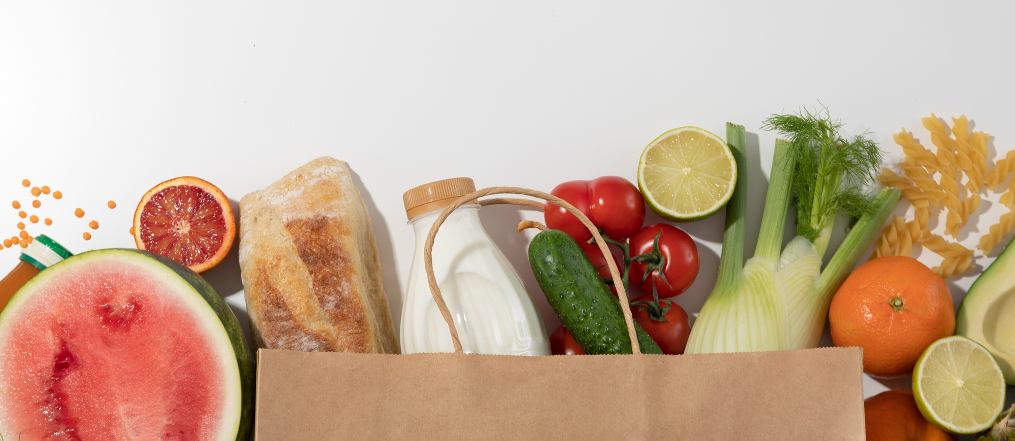 A brown paper bag filled with fresh groceries like watermelon, bread, milk, tomatoes, and more. ClicknCollect makes it easy to gather such diverse items efficiently.