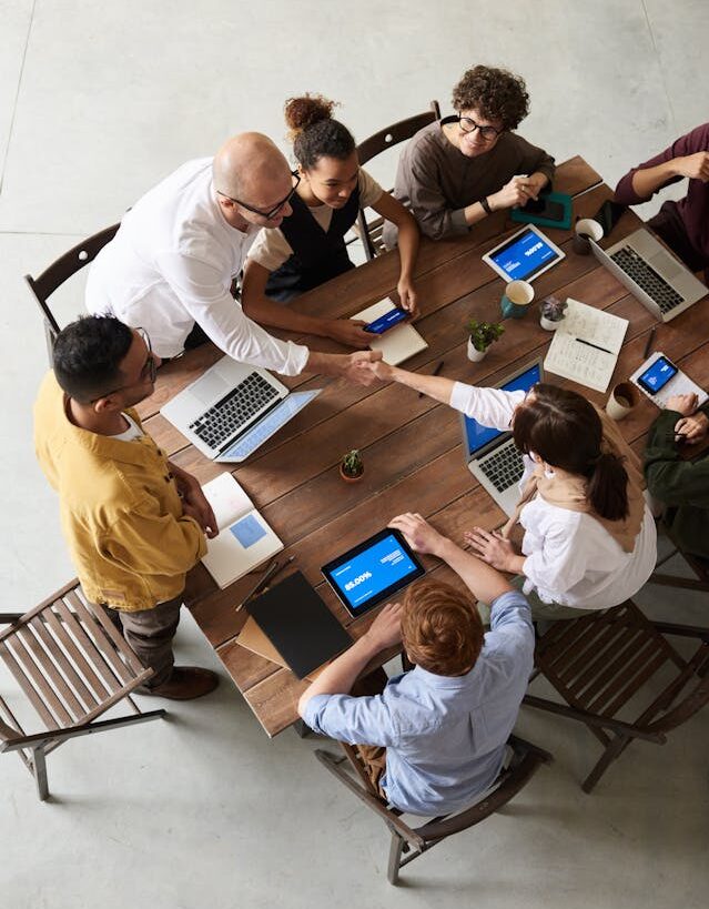 A diverse team of professionals collaborating on laptops in a modern office, showcasing global teamwork in providing worldwide services.