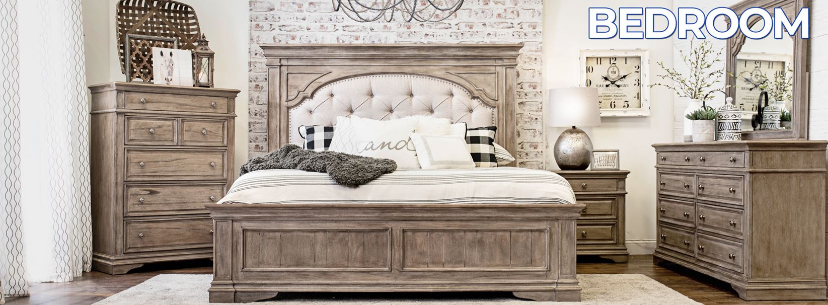 A rustic bedroom by Steve Silver Company featuring a tufted wooden bed, matching dressers, and nightstands, decorated with a gray throw, pillows, a clock, lamp, and plants. "BEDROOM" is displayed in the upper right corner.